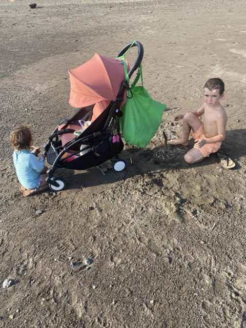 Coral pink Babyzen YoYo used as a beach stroller in Costa Rica with two kids