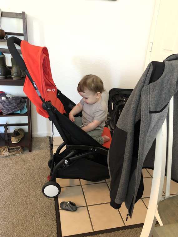 Baby seated in a red Babyzen YoYo travel stroller at home, packed for a trip