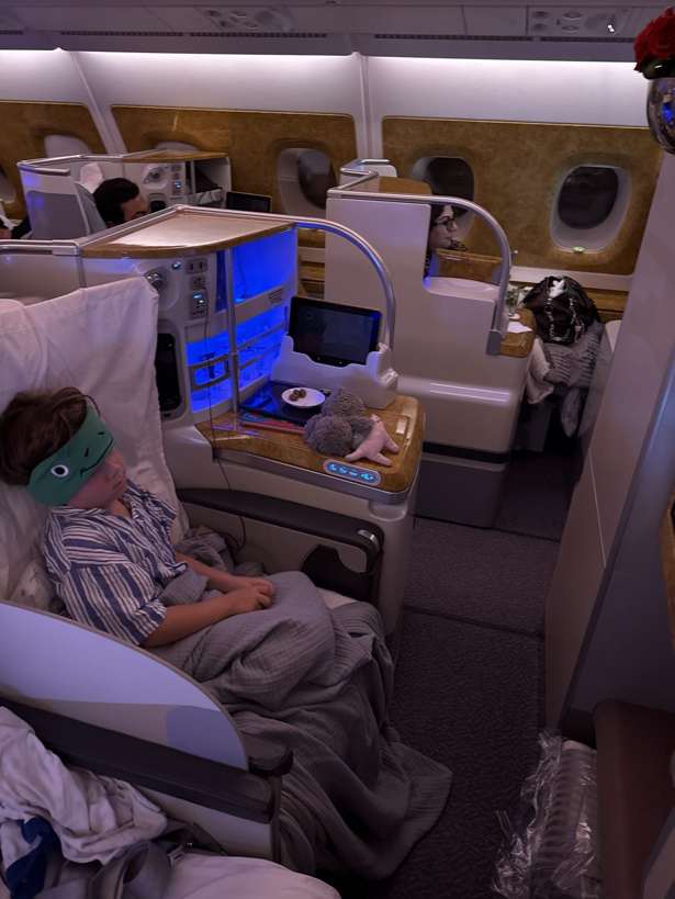 Toddler asleep wearing CozyPhones headband as a sleep mask on a flight