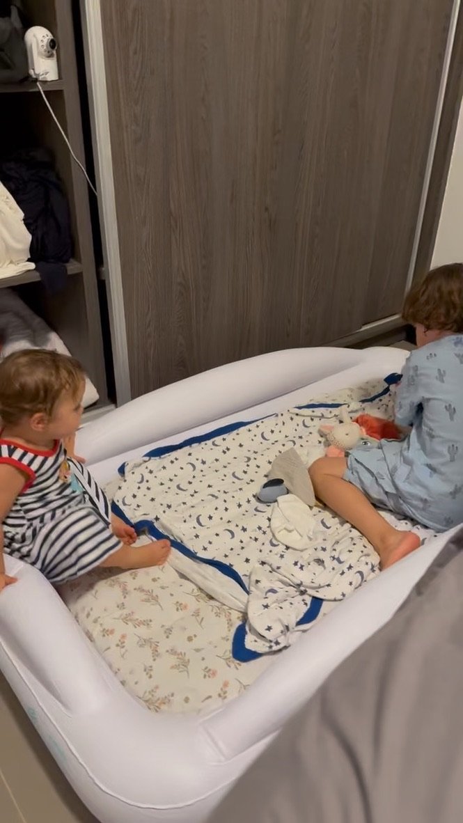 Toddler travel bed with tall 4-sided safety bumpers keeping two kids in